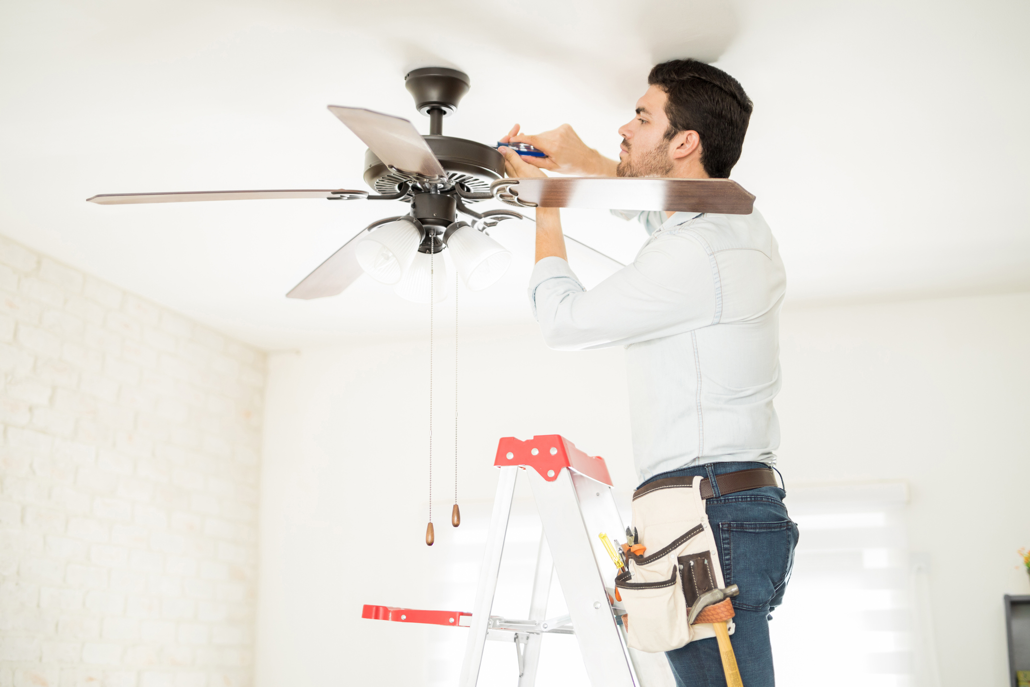 HVAC technician repairing a ceiling fan in a Michigan home