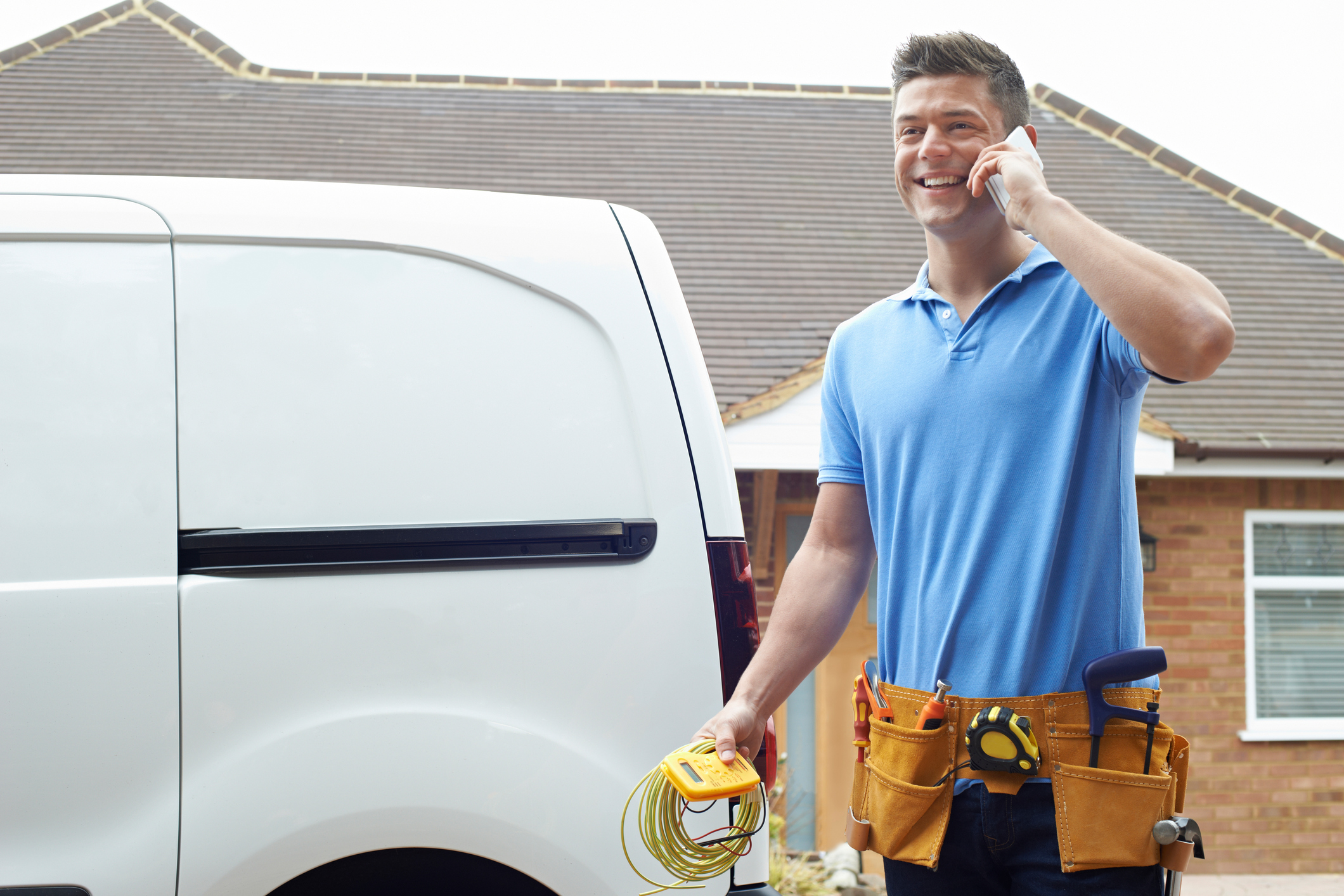 HVAC technician outside a Michigan home on the phone in front of a work van