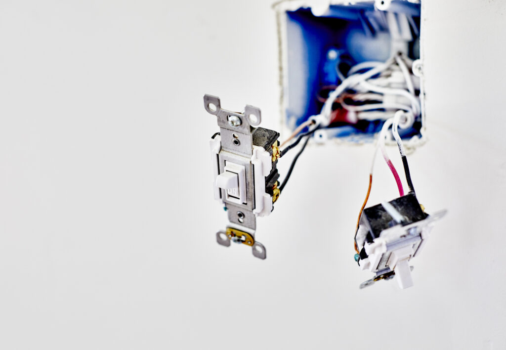 Light switches hanging from their wires in an open hole in the wall