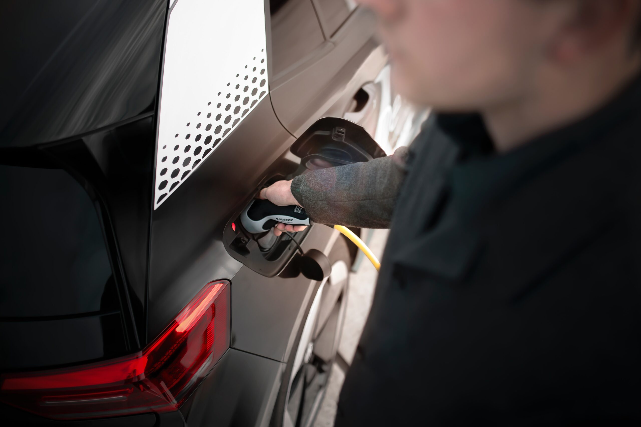 Man holding an EV charger as he charges his car